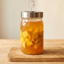 Mango pieces in a glass fermentation vessel